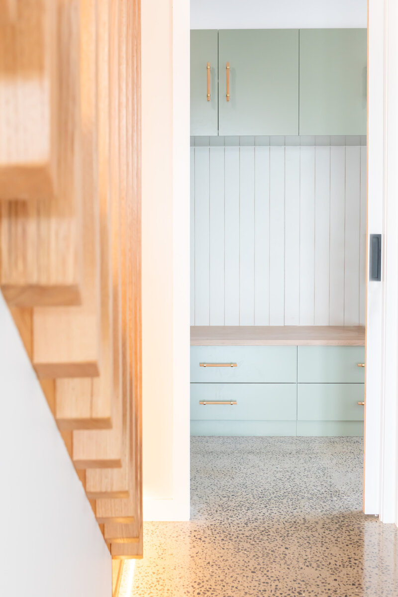 Timber staircase leading into concrete floor living area in custom home build