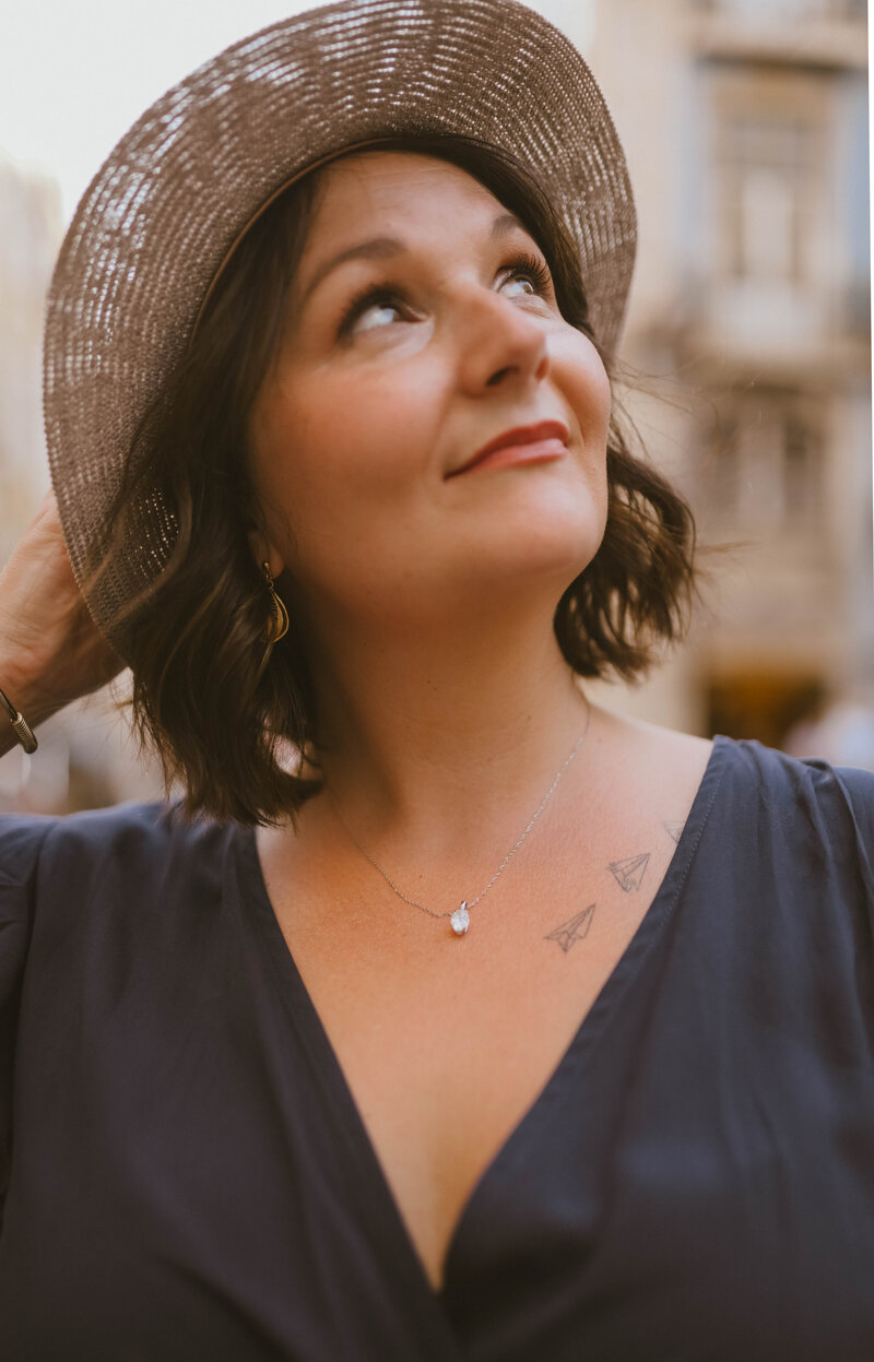 Maggie Dickens, LPCS, looking upward while wearing a hat outdoors, representing a compassionate therapist offering personalized online therapy and coaching for women in Texas and Florida.