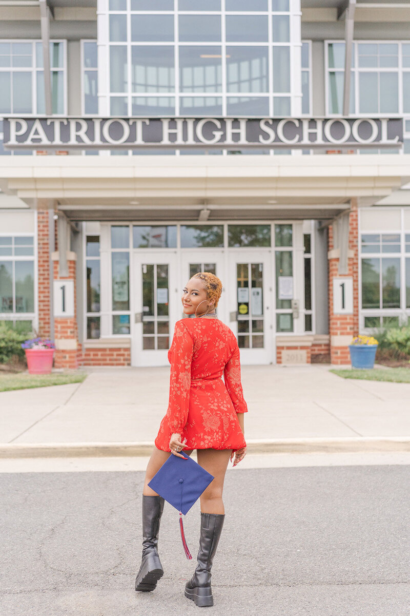 girl holding graduation cap outside her high school  taken by senior photographer in Nokesville, VA