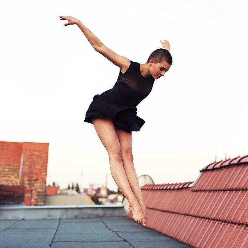 young female dancer flying in air on rooftop