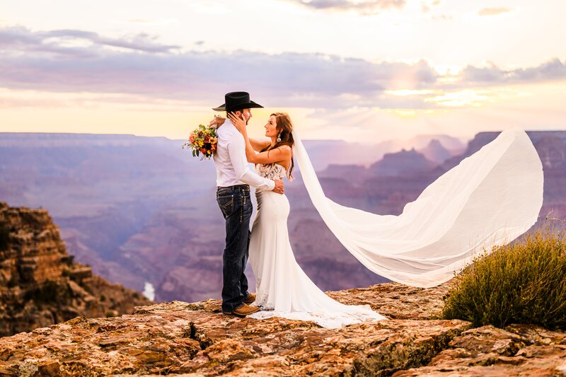 bride and groom looking at each other with purple sunset behind them at Grand Canyon wedding elopement