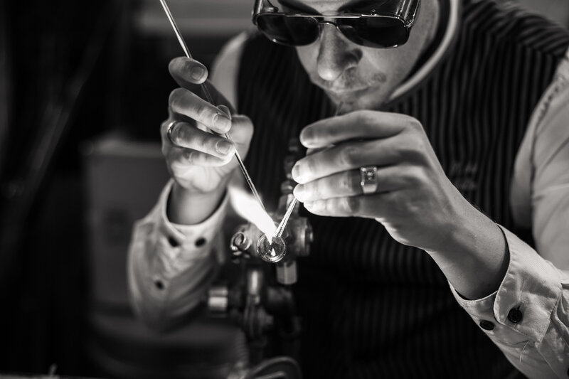 A glass artist shaping his creation using a burner.