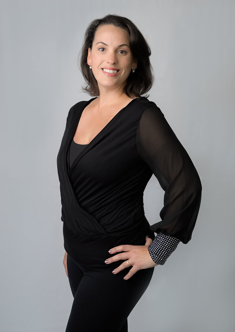 Photographer Elizabeth Benecki standing in front of a white background dressed in black.