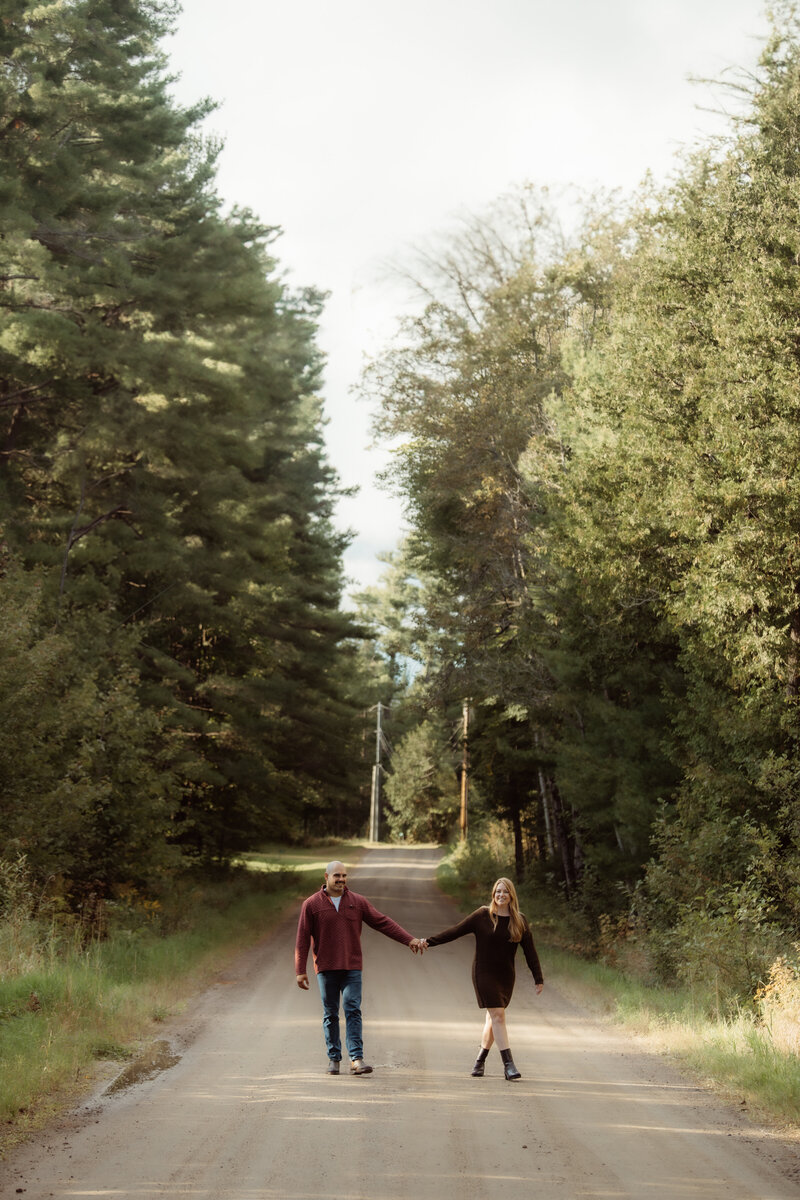Candid moment of a couple walking hand-in-hand across an open countryside field, captured with a wanderlust-driven lens