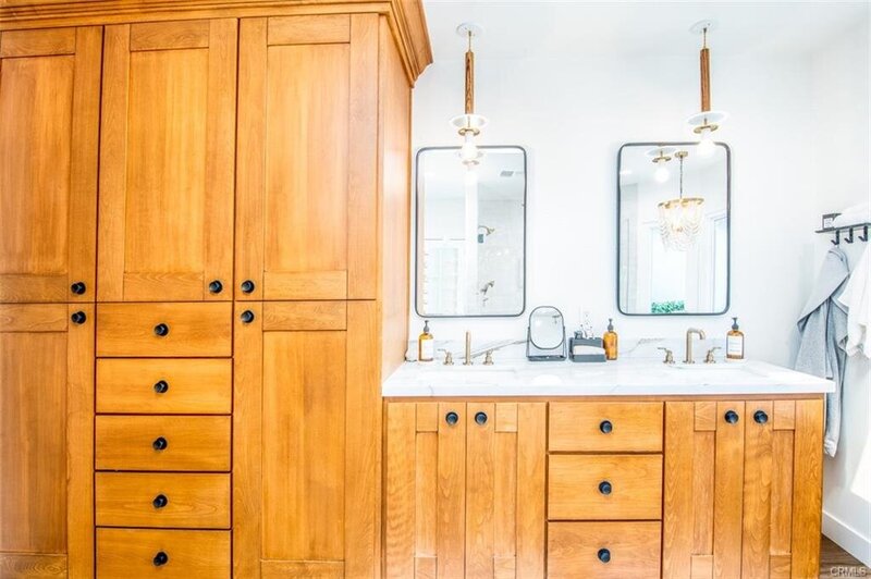 Sunlit master bathroom with bright wood cabinetry, black hardware, and funky modern mirrors for a bold, eclectic look.
