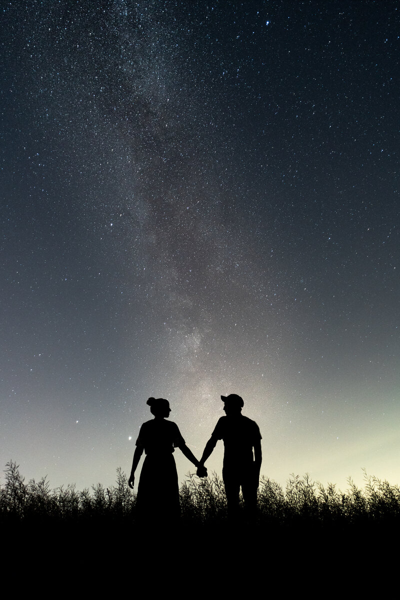 Couple holding hands in front of the Milky way