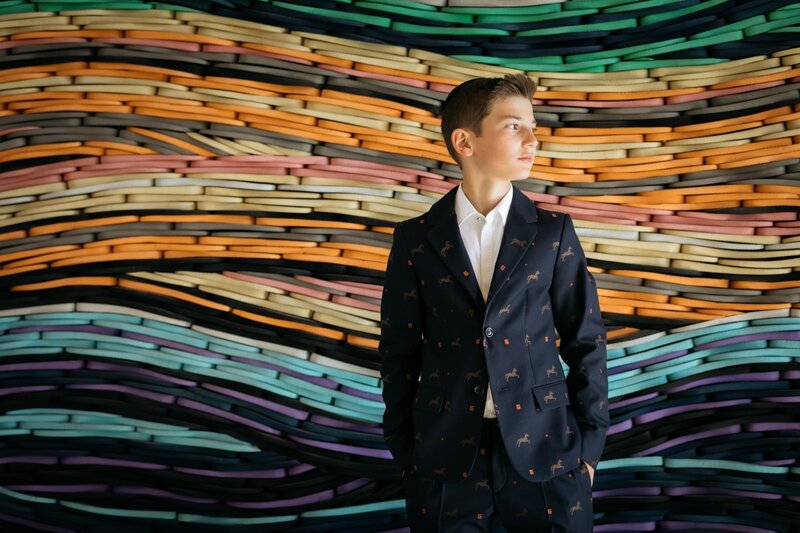 A boy looking off to the side while standing in front of a colorful wall