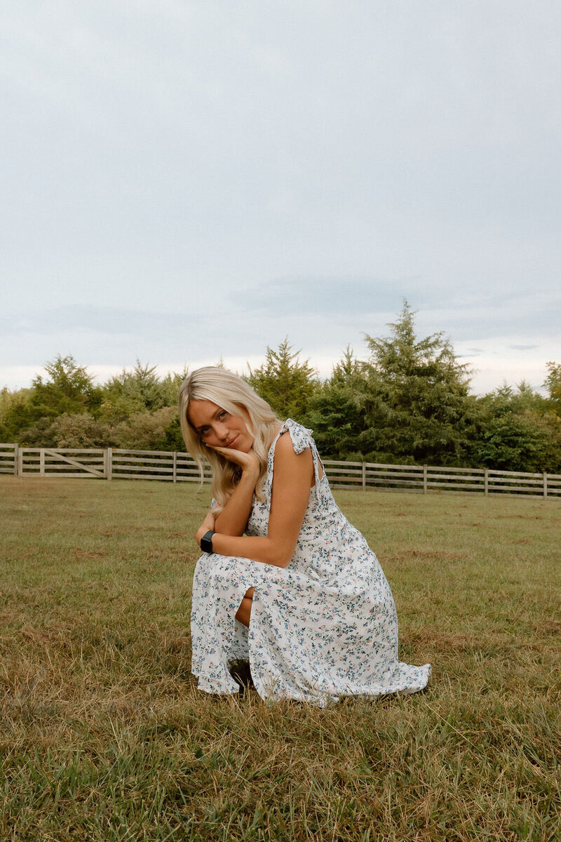 girl poses for senior photos in field in kansas city
