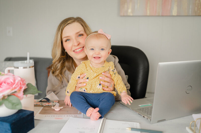 Erika holding her daughter on her desk