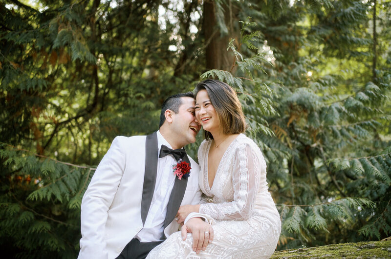 Groom rests his head on the bride's shoulders, laughing during a wedding portrait session