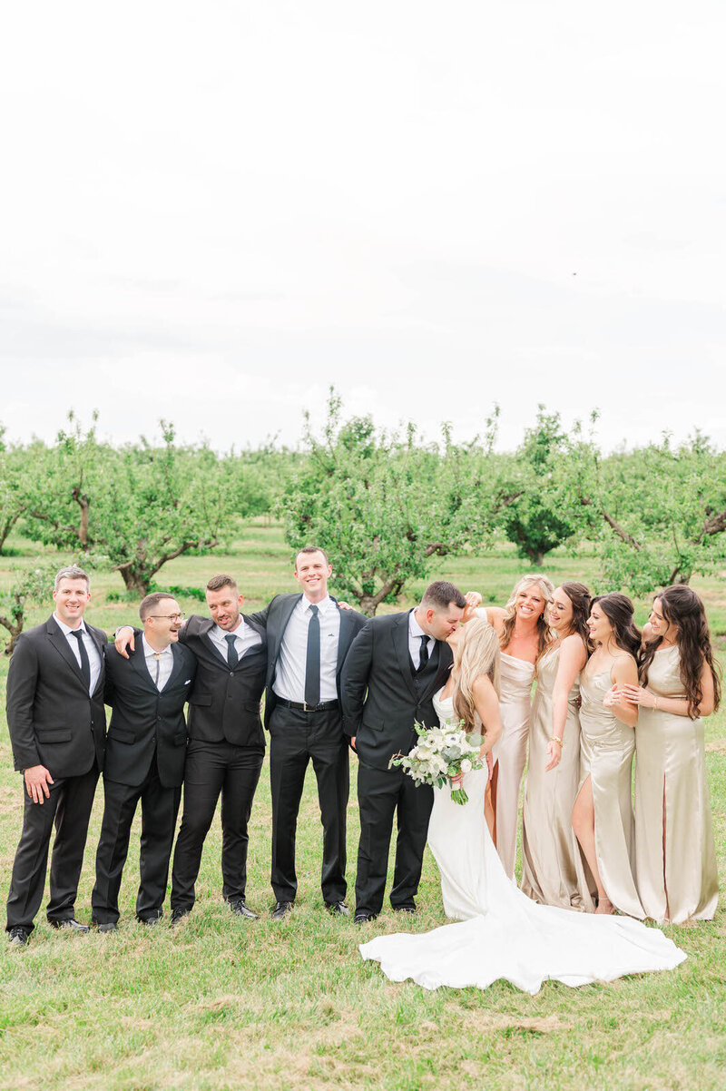 Bride and groom kiss on their wedding day with their bridal party