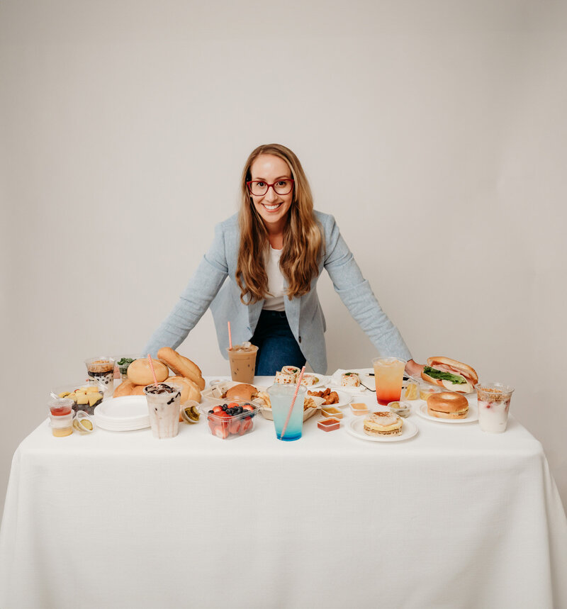 Rachel Toner, food sensory scientist and owner of Taste Strategy, standing next to table of food