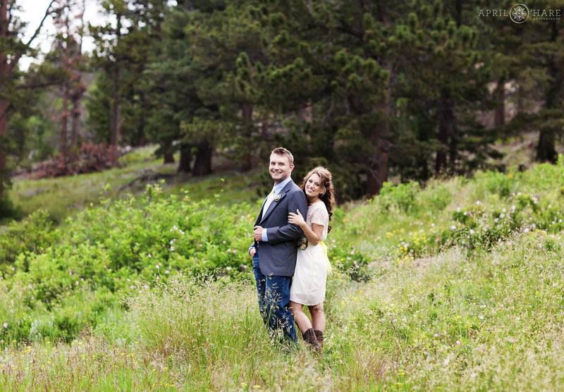 Couple poses in the pretty greenery at their summer elopement at Lily Lake in Colorado