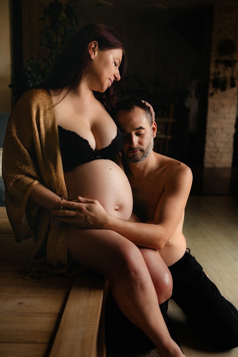 photo grossesse cocooning homme et femme en intérieur enlacés dans l'attente de bébé