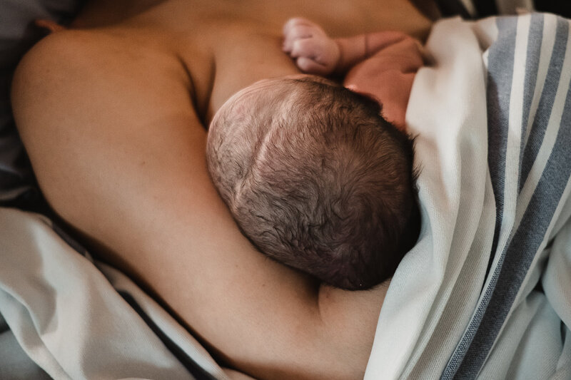 Close-up of a newborn’s head while breastfeeding, highlighting the peaceful bond and connection between mother and baby.