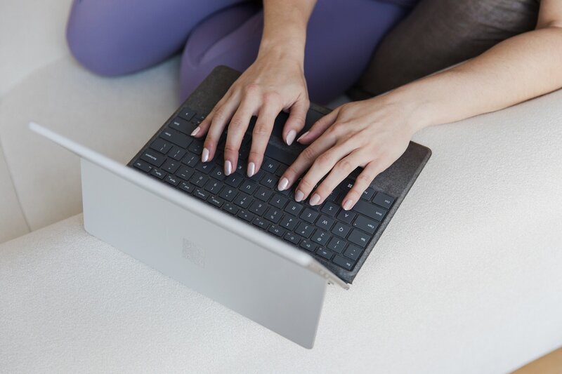 Hailey Ann Co Bookkeeper and somatic money coach for female entrepreneurs typing on a laptop.