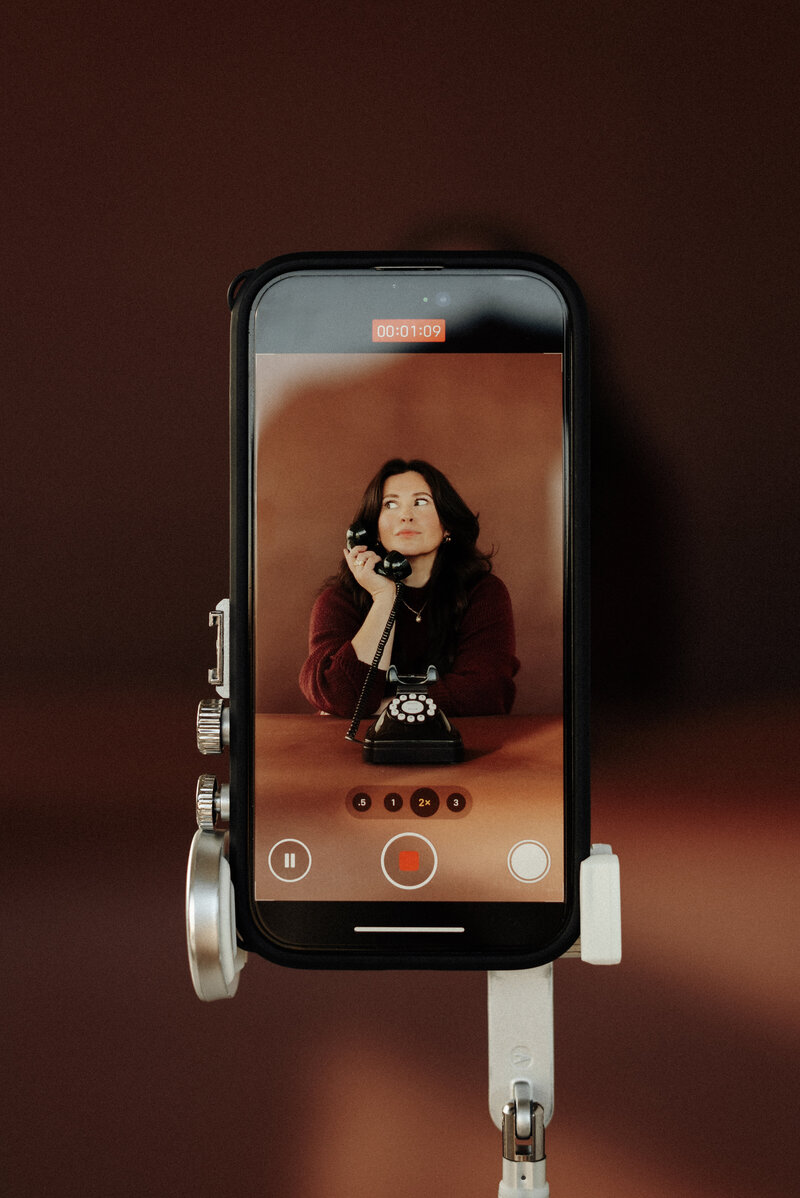 B-roll image captured on an iPhone of Elisabeth Eden holding a vintage phone during a branding photoshoot, blending retro style with modern technology.
