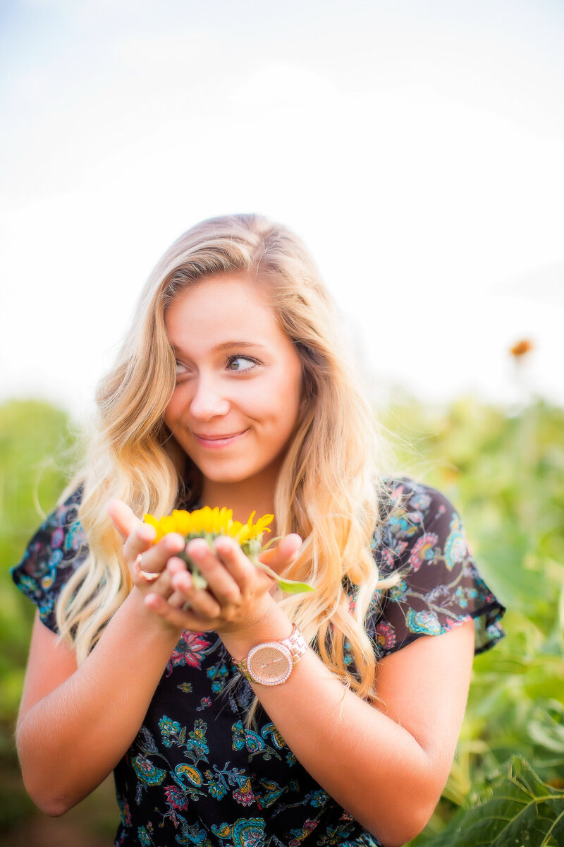 color image of female smirking with flowers in hand