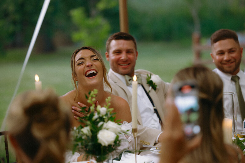 Couple on their wedding day laughing during speeches.