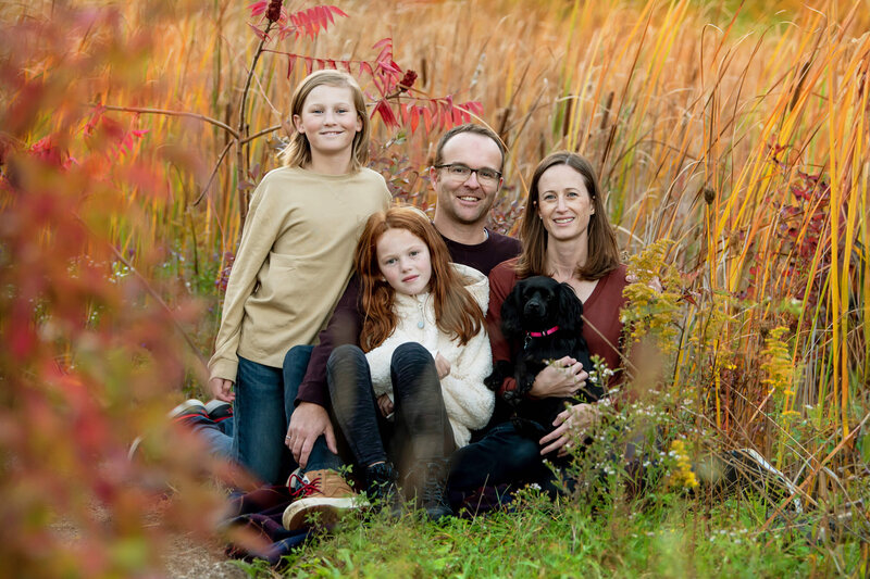 mom and dad sitting on the ground with their son daughter and dog for their fall family photos in Burlington, Ontario