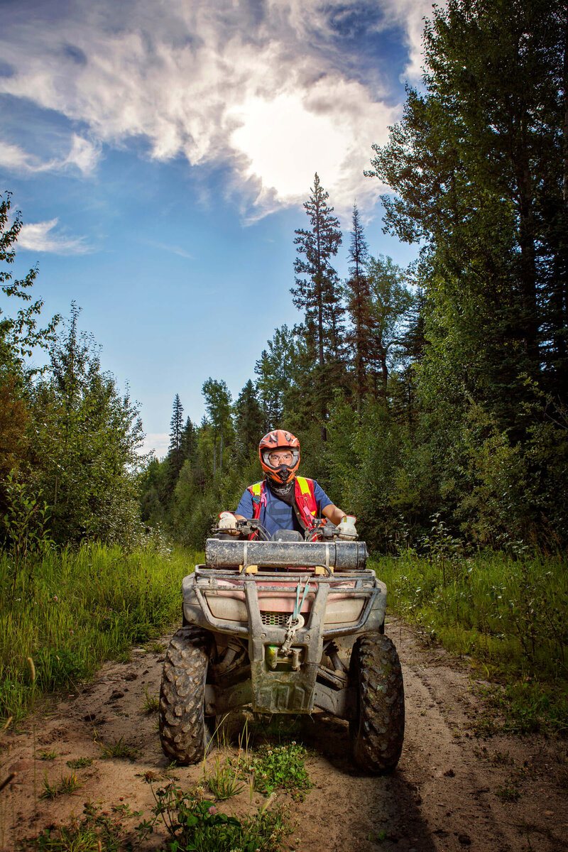 man on a quad with helmet in the forest