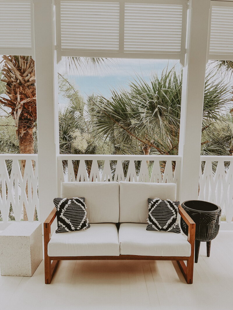 white patio with wooden furniture and black accent cushions