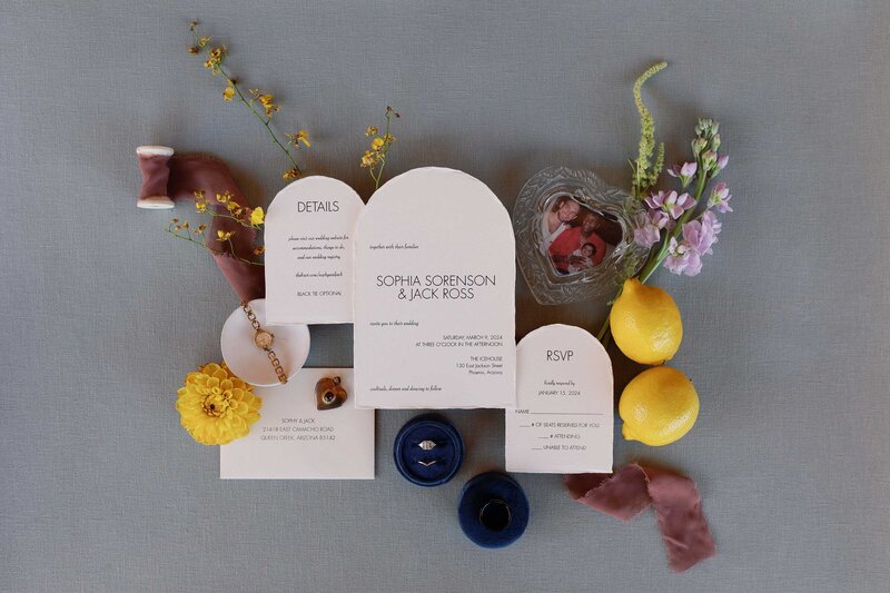 Wedding invitation styled with citrus fruit, colorful florals, and silk ribbon.