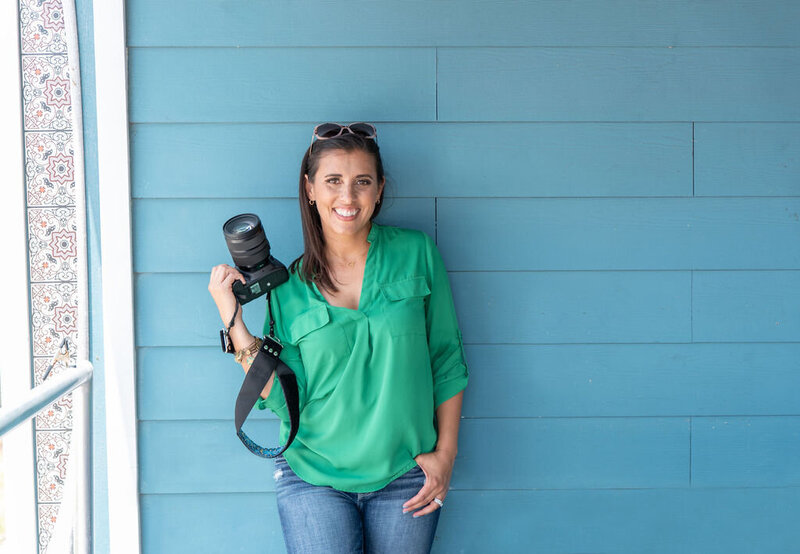 brand photo of woman against a blue wall holding her camera while standing next to a window captured by Orlando photographer