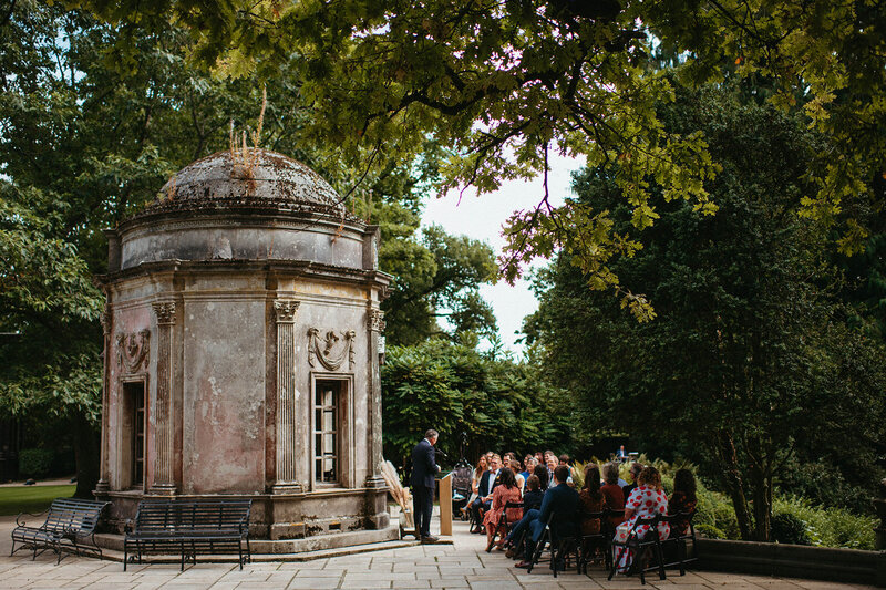 Intimate wedding party seated behind Roman Temple