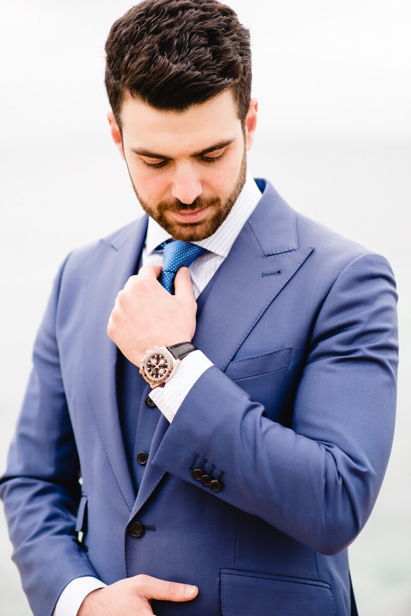 groom looking down while touching his tie