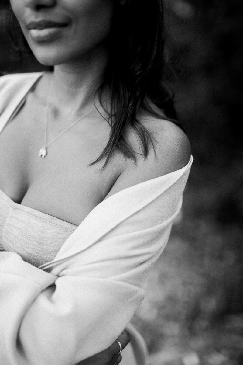 A black and white image of a woman wrapped in a light sweater, conveying warmth, comfort, and a serene approach to wellness.