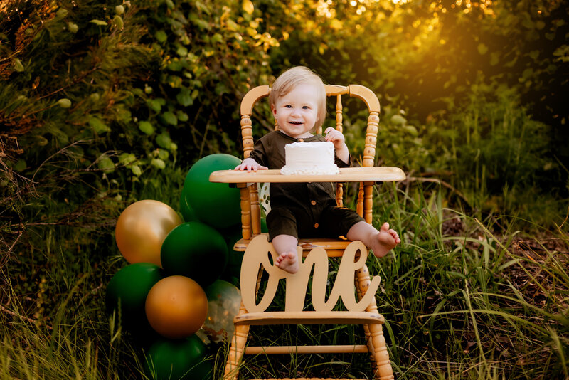 Cake Smash Photographer, a baby girl eats cake and sits before balloons