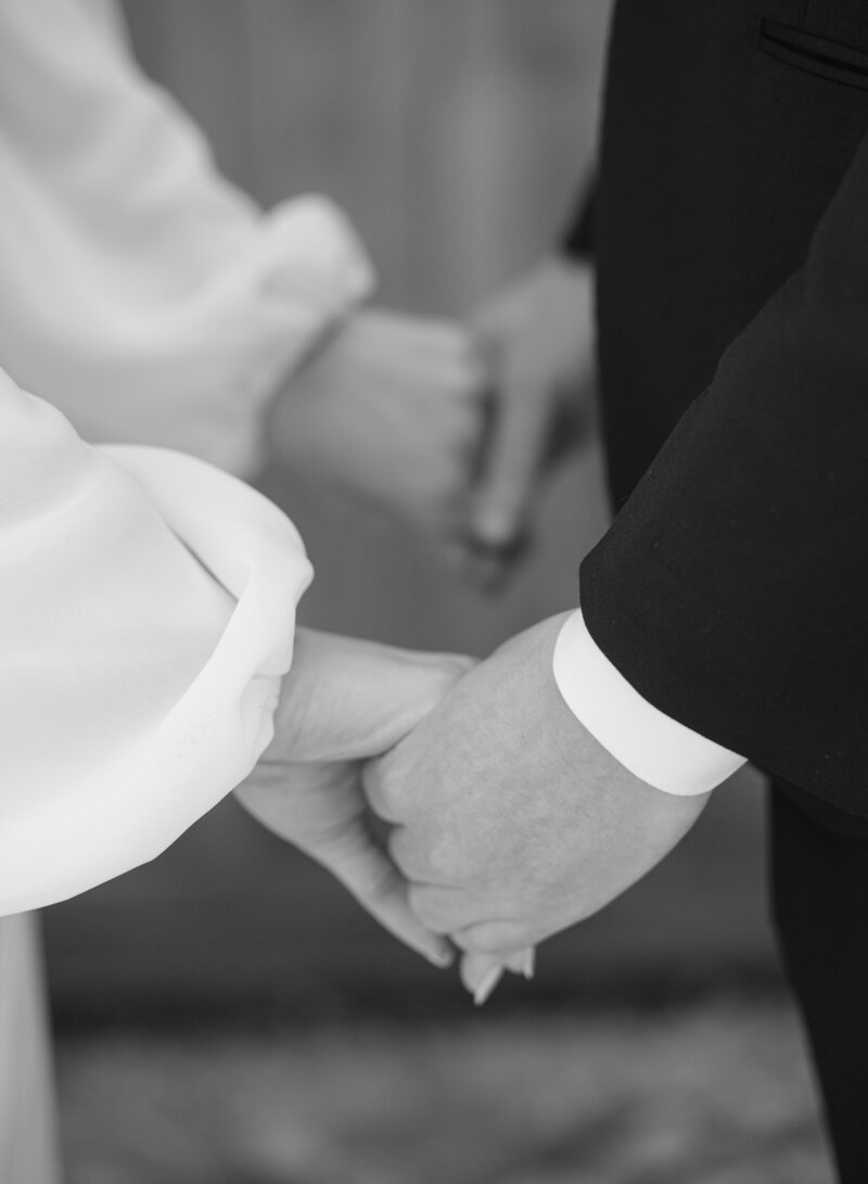 A black and white closeup image of a couple holding hands
