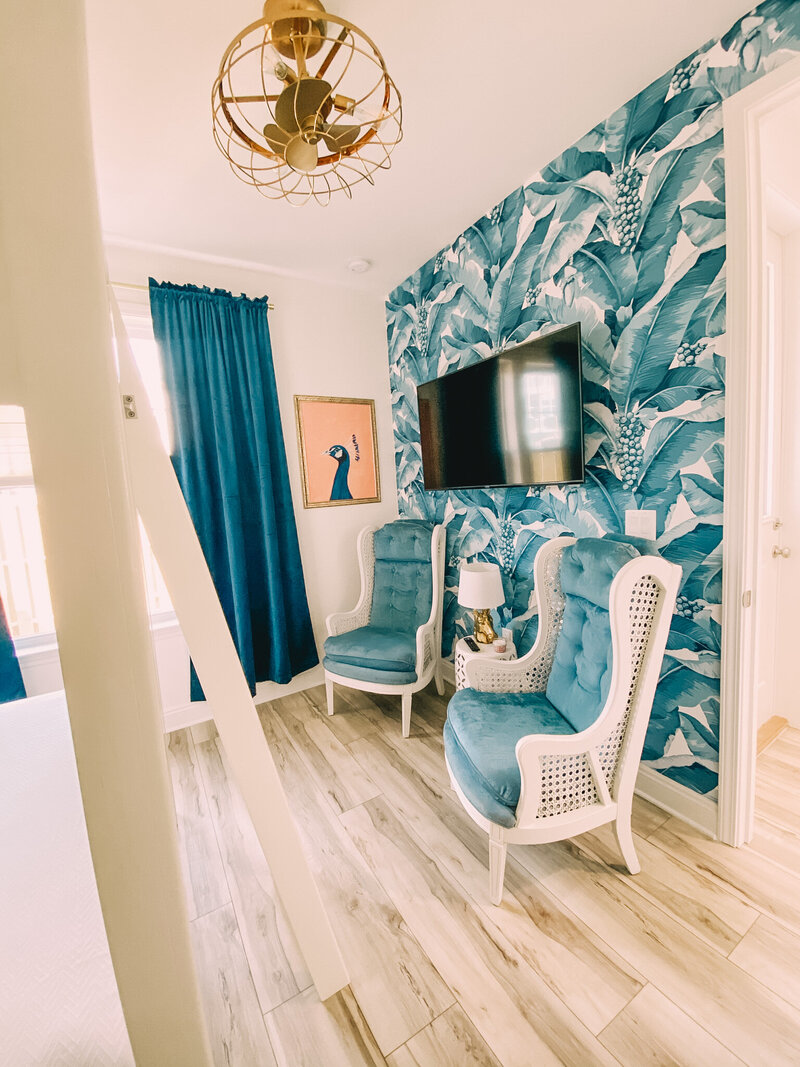 bedroom with blue palms wallpaper and vintage blue chairs