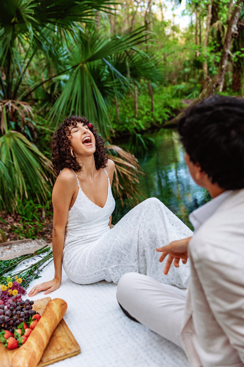 Shannon Lee, a Florida elopement photographer capturing a joyful and carefree moment of a bride laughing with her groom by the water in a lush, tropical setting.