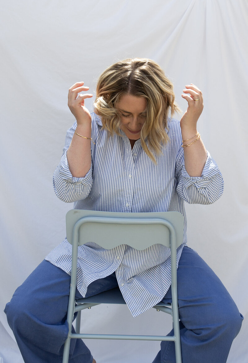 Graphic designer Bess Brownlee smiles in a blue chair outside in Missoula, Montana.