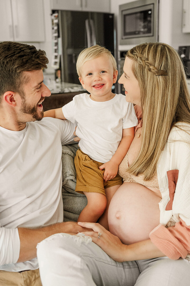 father and mother who is pregnant looking at their two year old son who is sitting between them by york pa photographer