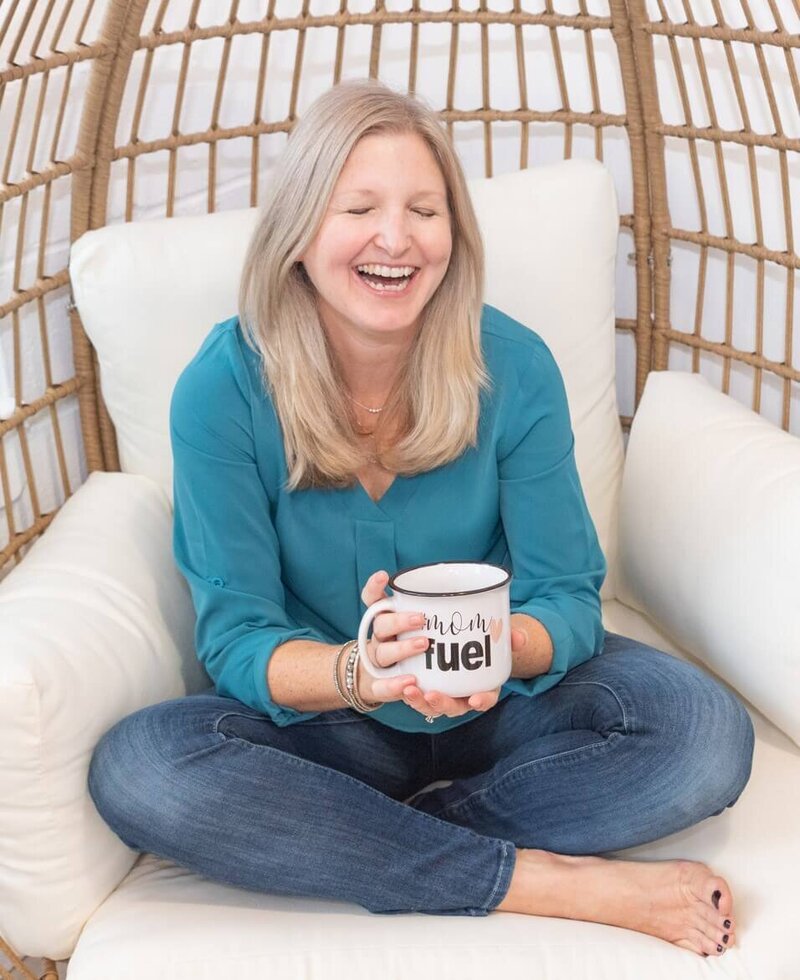 Maureen sitting on chair in jeans and teal blouse laughing