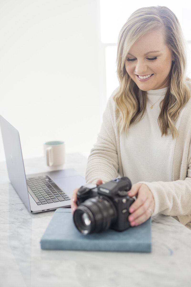 Krista Marie, a NYC brand photographer, picking up her camera and smiling