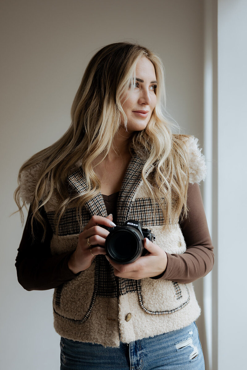 Meet Becca a Utah elopement photographer that is a specialist in Yosemite elopements. Becca is wearing a cowgirl hat and holding her camera that she takes amazing photographs with.