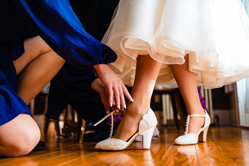 A bridesmaid helps put the brides shoes on before the ceremony