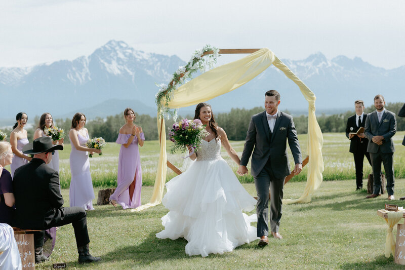 A couple standing together holding a bouquet of flowers after their wedding ceremony. 