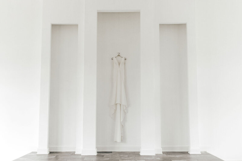wedding dress hanging up on large white wall