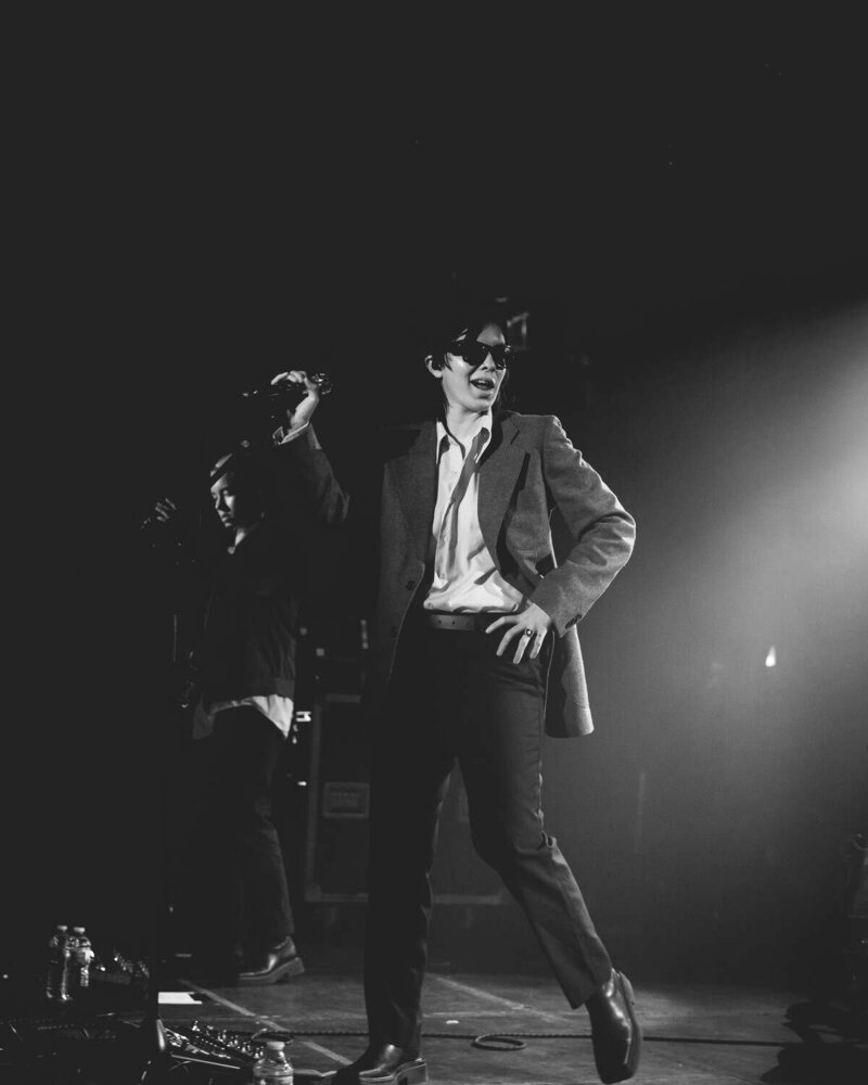 Lead singer of the Aces places hand on hip and looks away from crowd