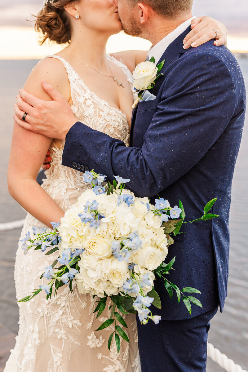 bride and groom kissing with a focus on the bride's white and blue bouquet