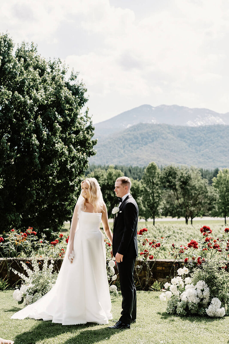 Bride and groom at ceremony on white stage under trees