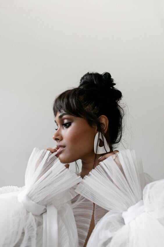 Bride with wedding hair updo and fringed sleeves.