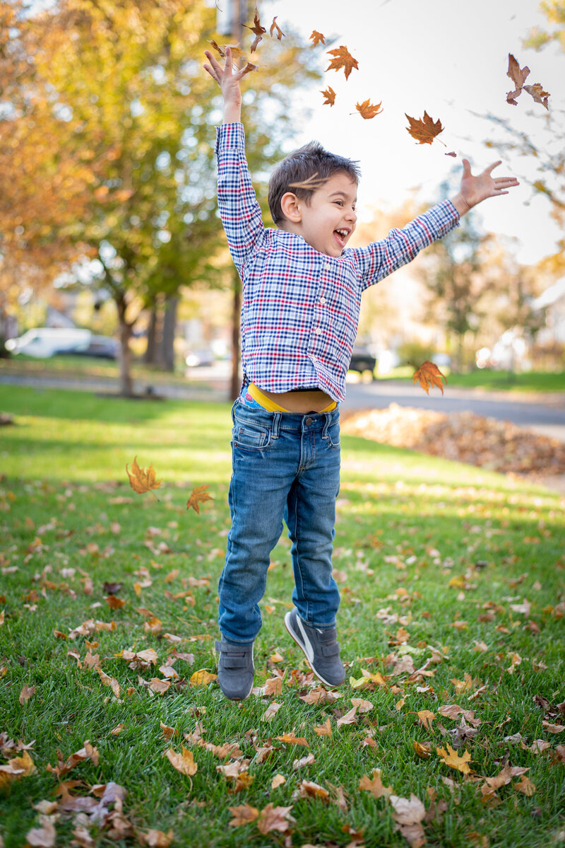 Photography By Sherifa-Family Portrait-little boy jumping with fall leaves