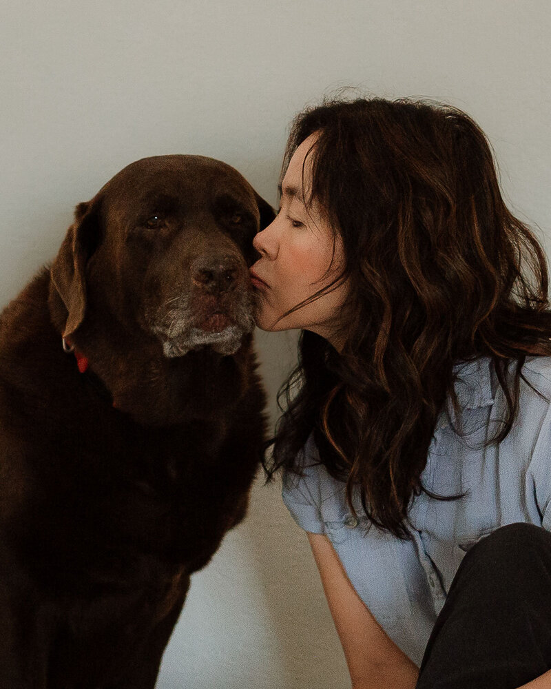Portrait of a woman kissing her chocolate Labrador taken in Menifee, California.