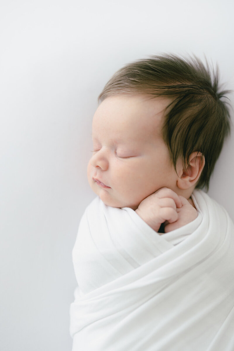 baby with bow on her head smiling at camera in-home newborn photography session captured by Tampa lifestlyle photographer.